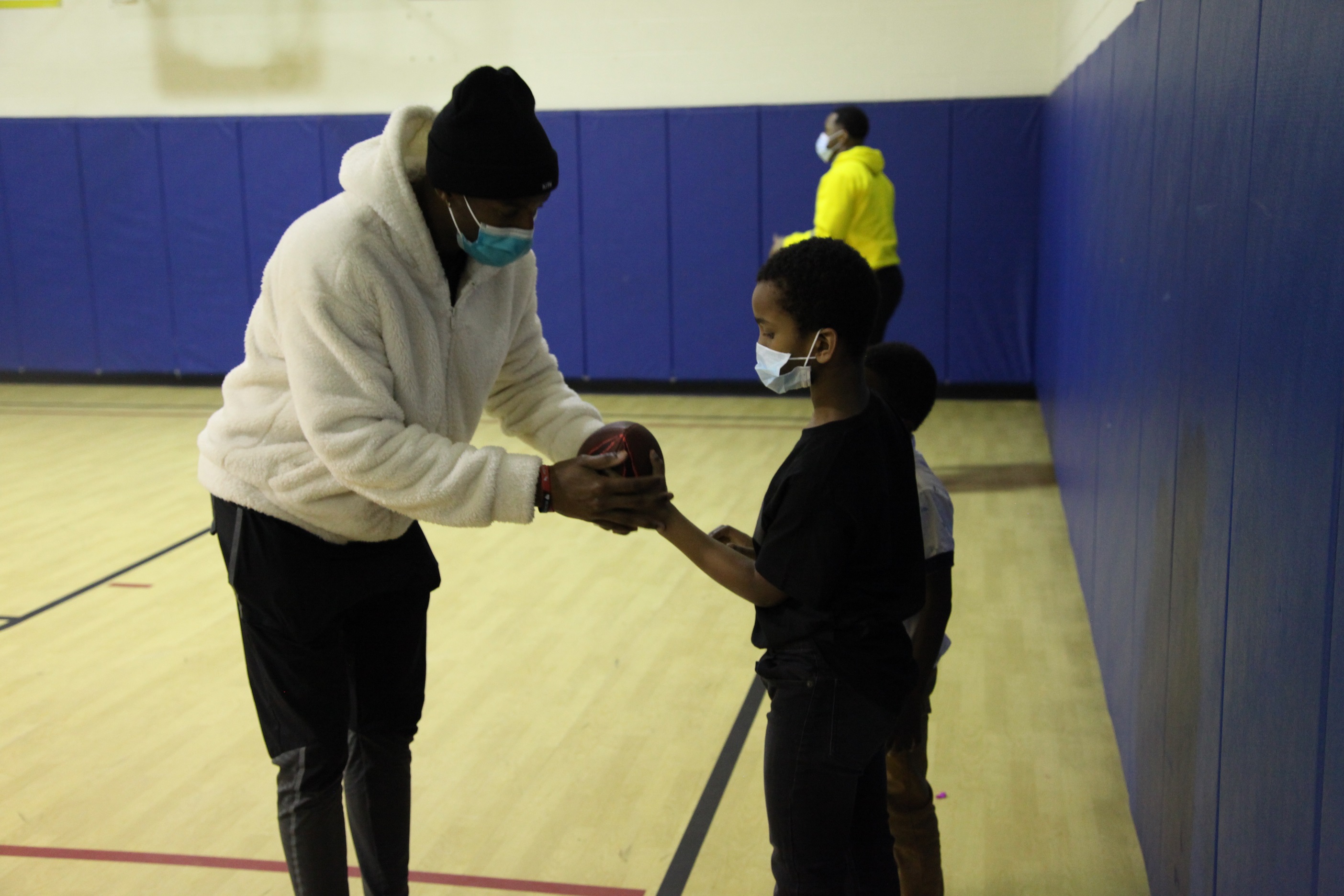 A man holds a football, showing a young boy how to hold it correctly