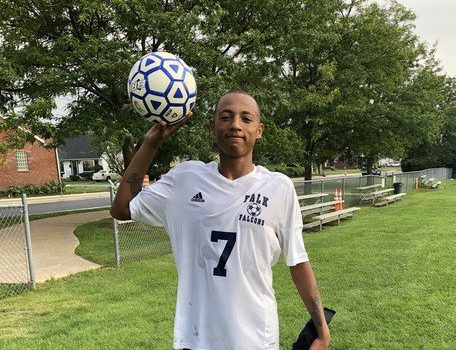 A soccer player wearing the number seven proudly holds a ball in the air