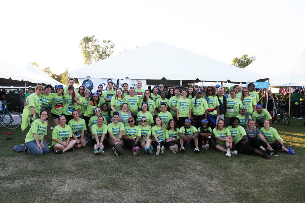 A large group wearing green Corporate Challenge shirts poses for a photo