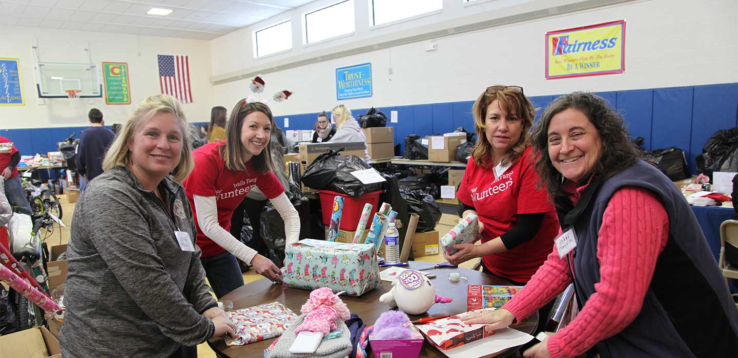 Four women wrapping gifts at a table for Adopt-a-Family