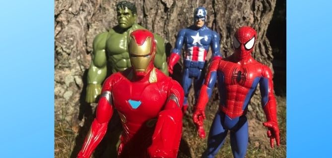 Superhero action figures lined up on a lawn