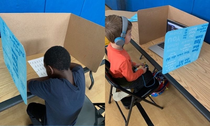 Side-by-side of two young boys sitting at remote learning stations