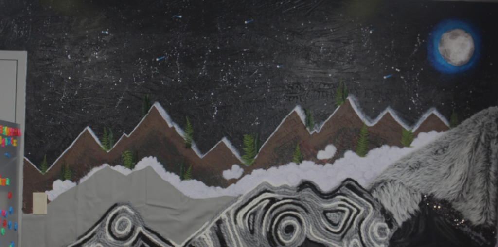 a wall of different textures shows a nighttime scene by mountains