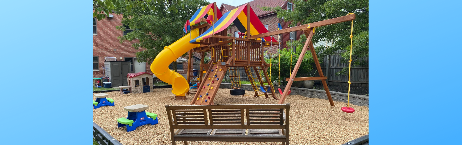 A wood bench sits in the foreground of a multicolored playground