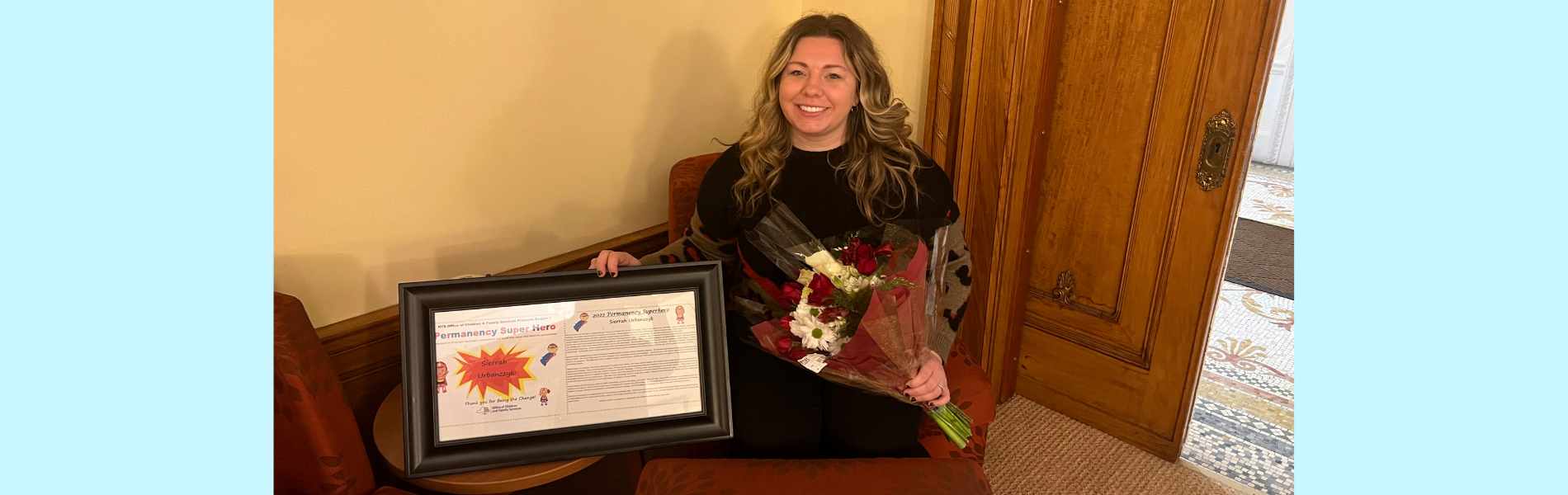 Sierrah holds a framed certificate in one hand and a bouquet in another